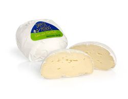 KI generiert: Das Bild zeigt ein Stück weißen Käse, das auf einer schwarzen Schieferplatte in vier Portionen geschnitten ist, daneben ist eine verpackte, identische Käserolle abgebildet.