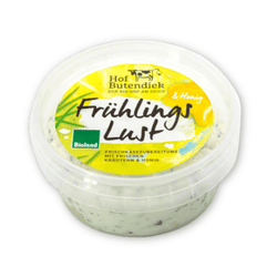 KI generiert: Auf dem Bild befindet sich eine durchsichtige Plastikverpackung mit Ziegenfrischkäse, der mit Kräutern und rosa Pfefferkörnern verfeinert ist. Das Etikett trägt die Aufschrift "ZiegenFRISCHKÄSE" der Marke Biovela.