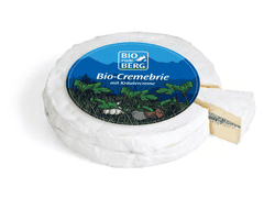 KI generiert: Das Bild zeigt ein Stück weißen Käse, das auf einer schwarzen Schieferplatte in vier Portionen geschnitten ist, daneben ist eine verpackte, identische Käserolle abgebildet.