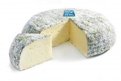 KI generiert: Das Bild zeigt ein Stück weißen Käse, das auf einer schwarzen Schieferplatte in vier Portionen geschnitten ist, daneben ist eine verpackte, identische Käserolle abgebildet.
