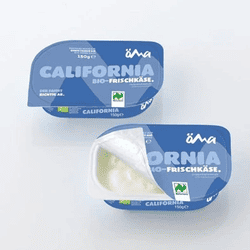 KI generiert: Auf dem Bild befindet sich eine durchsichtige Plastikverpackung mit Ziegenfrischkäse, der mit Kräutern und rosa Pfefferkörnern verfeinert ist. Das Etikett trägt die Aufschrift "ZiegenFRISCHKÄSE" der Marke Biovela.