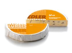 KI generiert: Das Bild zeigt ein Stück weißen Käse, das auf einer schwarzen Schieferplatte in vier Portionen geschnitten ist, daneben ist eine verpackte, identische Käserolle abgebildet.