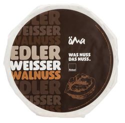 KI generiert: Das Bild zeigt ein Stück weißen Käse, das auf einer schwarzen Schieferplatte in vier Portionen geschnitten ist, daneben ist eine verpackte, identische Käserolle abgebildet.