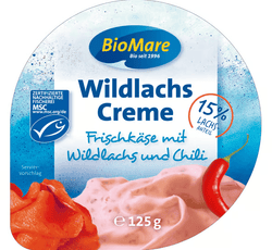 KI generiert: Auf dem Bild befindet sich eine durchsichtige Plastikverpackung mit Ziegenfrischkäse, der mit Kräutern und rosa Pfefferkörnern verfeinert ist. Das Etikett trägt die Aufschrift "ZiegenFRISCHKÄSE" der Marke Biovela.