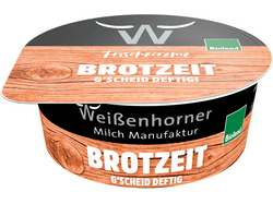 KI generiert: Auf dem Bild befindet sich eine durchsichtige Plastikverpackung mit Ziegenfrischkäse, der mit Kräutern und rosa Pfefferkörnern verfeinert ist. Das Etikett trägt die Aufschrift "ZiegenFRISCHKÄSE" der Marke Biovela.