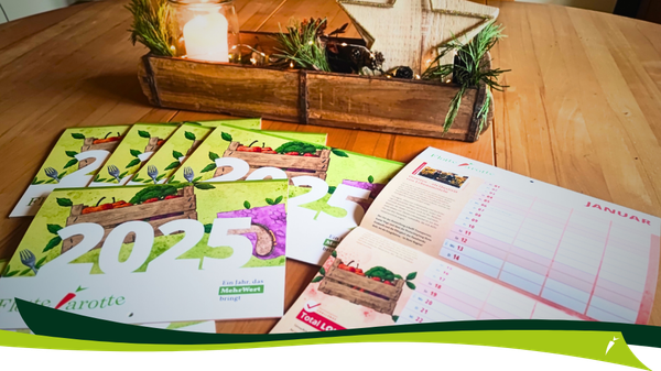 KI generiert: Das Bild zeigt mehrere Kalender für das Jahr 2025 mit Illustrationen von Gemüse auf einem Tisch. Im Hintergrund ist eine weihnachtliche Dekoration mit einer Kerze in einem Holzbehälter sichtbar.