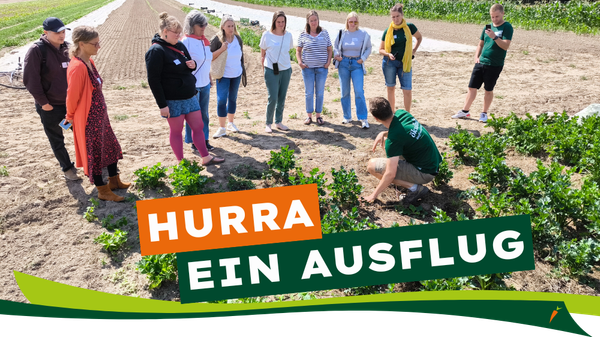 KI generiert: Eine Gruppe bei einer Outdoor-Führung auf einem Feld. Text: "HURRA, EIN AUSFLUG".