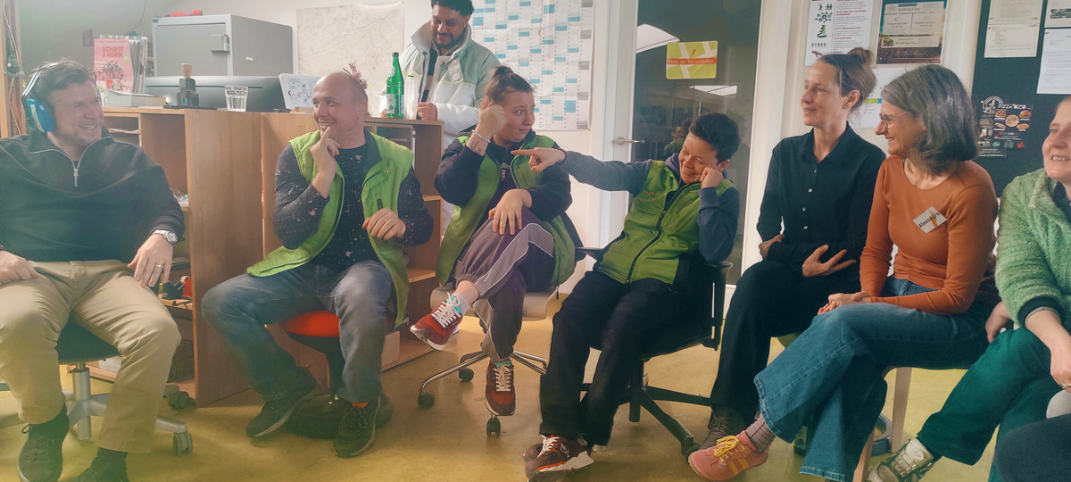 KI generiert: Eine Gruppe von Menschen sitzt lachend zusammen in einem Raum.