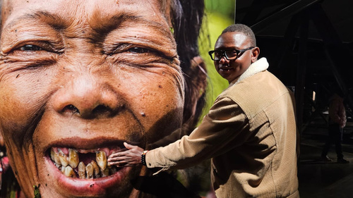 KI generiert: Ein Mann posiert vor einem großformatigen Porträt einer lächelnden älteren Frau.