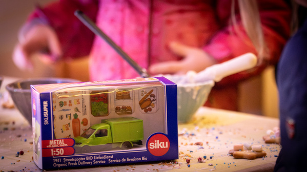 KI generiert: Ein Spielzeug-LKW in einer Verpackung liegt auf einem Tisch beim Backen. Text: "Organic Fresh Delivery Service."