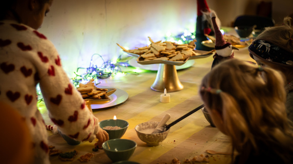 KI generiert: Kinder dekorieren Kekse an einem Tisch mit Lichtern.