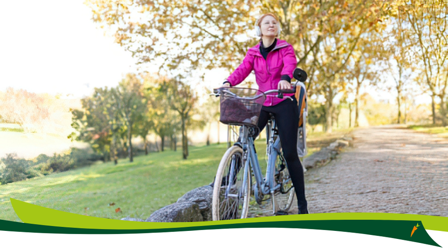 KI generiert: Eine Person im pinken Jacke steht mit einem Fahrrad auf einem Weg in einem herbstlichen Park.