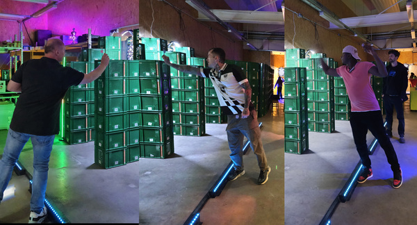 KI generiert: Drei Personen stoßen jeweils eine Kiste in einem beleuchteten Raum um.