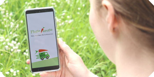 KI generiert: Ein Mensch hält ein Smartphone mit "Flotte Karotte" App-Logo vor grünem Hintergrund. Text: "Flotte Karotte".