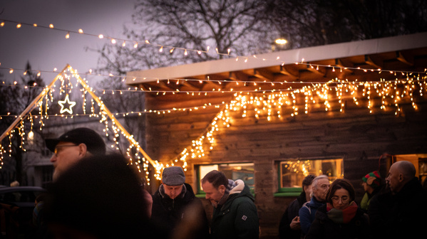 KI generiert: Menschen auf einem Weihnachtsmarkt, beleuchtet mit Lichterketten und einem Stern.