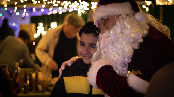 KI generiert: Ein Kind mit Weihnachtsmann in festlicher Umgebung voller Lichter.