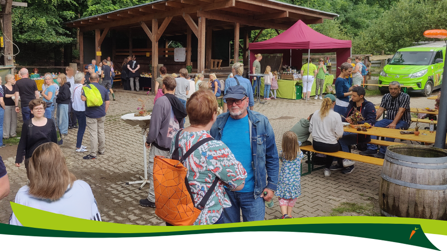 KI generiert: Eine größere Gruppe von Menschen auf einer Veranstaltung im Freien mit Ständen und Sitzgelegenheiten.