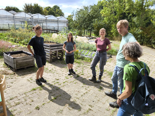 KI generiert: Drei Personen in einem Garten, umgeben von blühenden Pflanzen und Blumenfeldern.