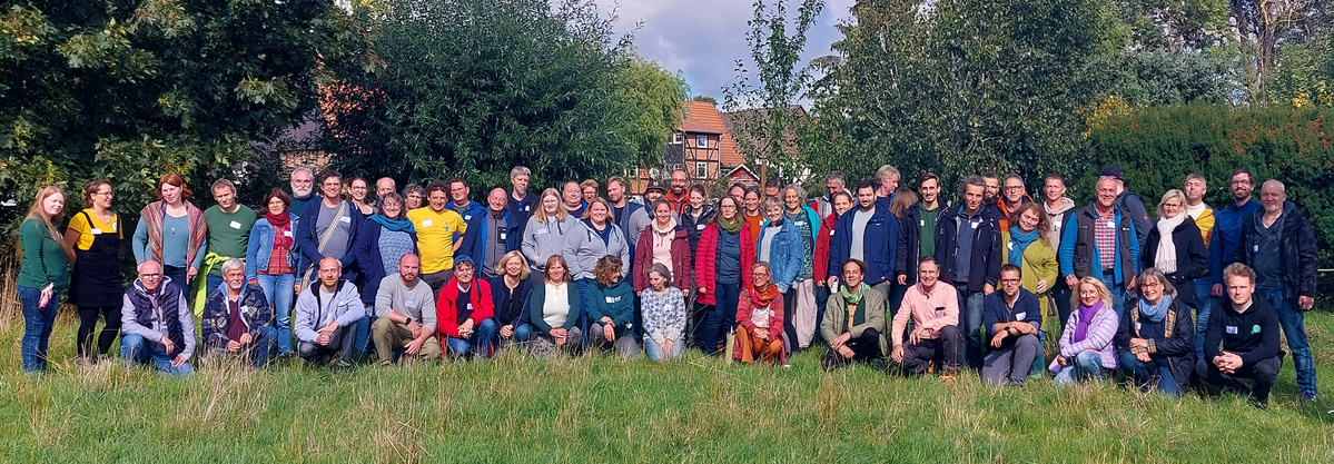 KI generiert: Eine große Gruppe Menschen posiert draußen auf einer Wiese.