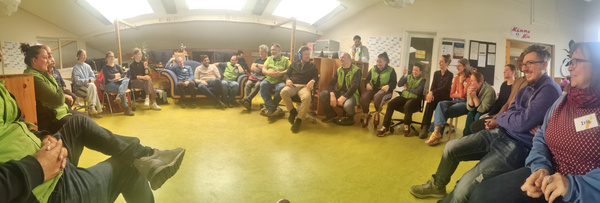 KI generiert: Eine Gruppe von Menschen sitzt im Kreis und diskutiert in einem Raum.