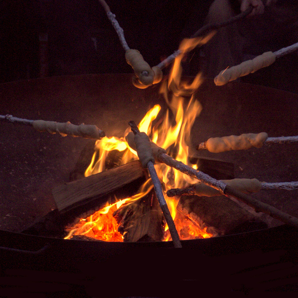 KI generiert: Stockbrot wird über einem offenen Lagerfeuer gebacken.
