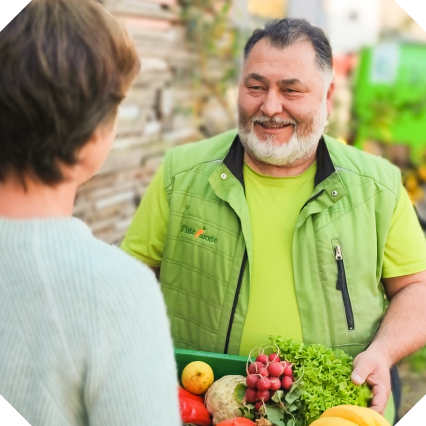 KI generiert: Ein lachender Mann übergibt einer Person eine Kiste mit frischem Gemüse. Text auf der Jacke: "Frischekiste".