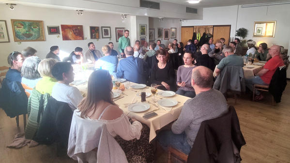 KI generiert: Menschen sitzen in einem Restaurant an einem großen Tisch und unterhalten sich lebhaft.