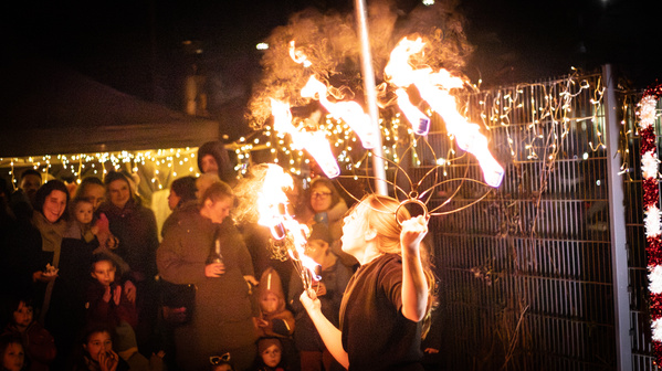 KI generiert: Eine Feuershow wird von einer Künstlerin vor einer Zuschauergruppe gezeigt.