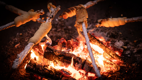 KI generiert: Stockbrot wird über einem offenen Lagerfeuer gebacken.