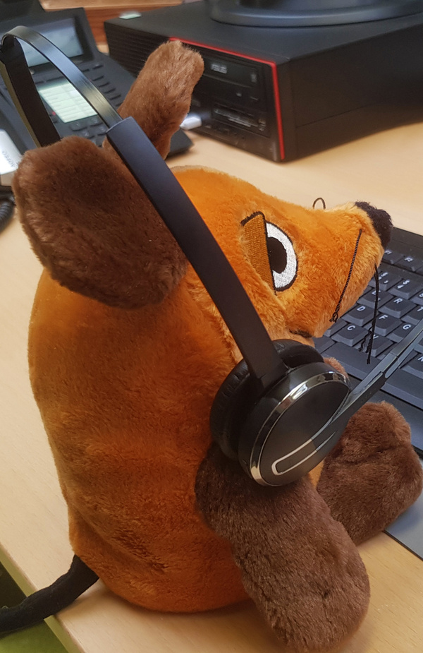 KI generiert: Ein Plüschtier mit Kopfhörern sitzt vor einer Tastatur.