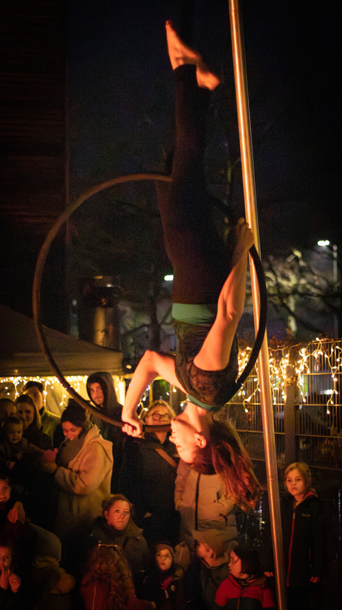 KI generiert: Eine Akrobatin führt Kunststücke in einem Reifen vor Publikum auf.