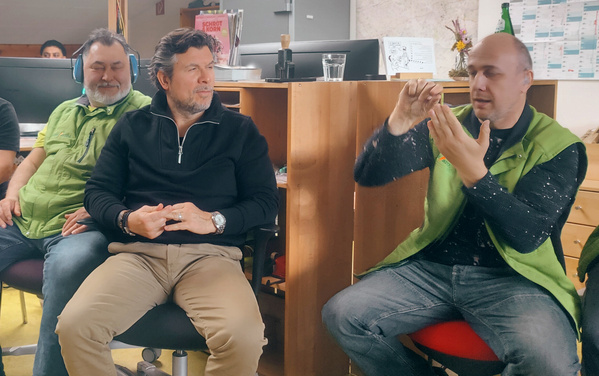 KI generiert: Drei Männer sitzen in einem Büro und diskutieren miteinander.