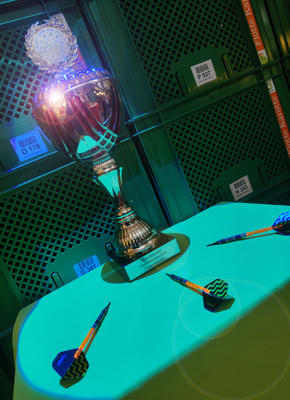 KI generiert: Ein Pokal auf einem Tisch mit drei Darts. Text: „Wanderpokal Dartsverein Pacific Center“.